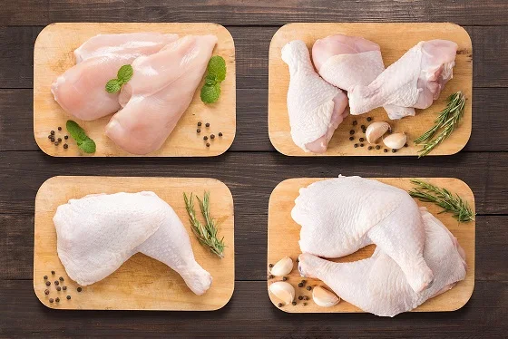 Morceaux de poulet découpés — blancs, pilons et cuisses — présentés sur des planches en bois