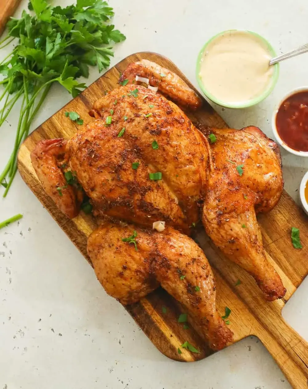 Poulet fumé doré servi sur une planche en bois, avec ses sauces